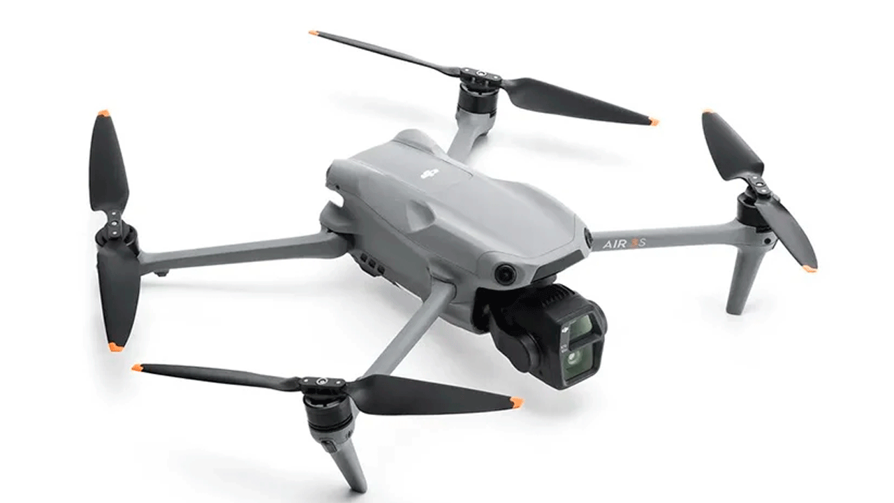 Квадрокоптер DJI Air 3S серого цвета с четырьмя черными пропеллерами с оранжевыми наконечниками и встроенной двойной камерой на шарнирном подвесе