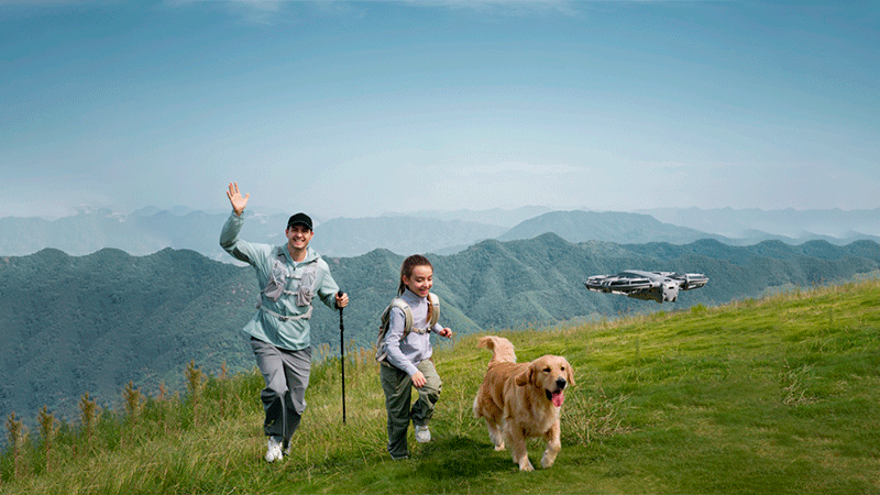 DJI Neo 2 следует за семьей с собакой во время прогулки в горах, снимая их движение в режиме ActiveTrack