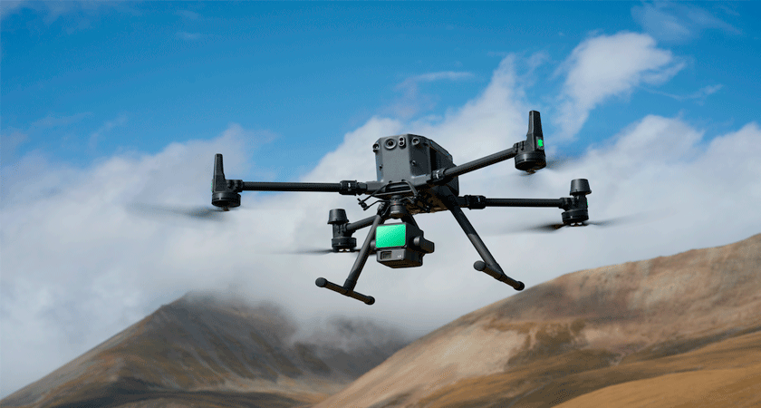 Квадрокоптер DJI с установленным лидаром DJI Zenmuse L2 летит на фоне гор и облаков
