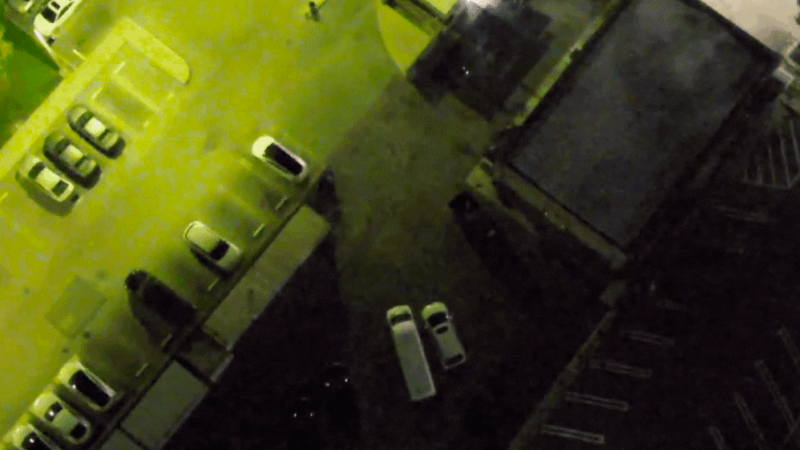 Ночной вид с дрона DJI в режиме Night Scene: парковка и автомобили, освещённые фонарями, с видимыми инфракрасными маяками, позволяющими распознавать членов спасательной команды в темноте