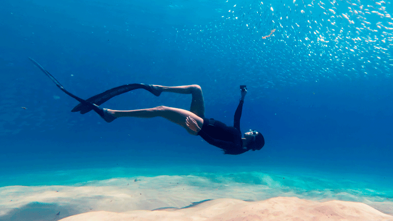 Фридайвер под водой снимает на DJI Osmo Action 6, показывая водонепроницаемость камеры на глубине.